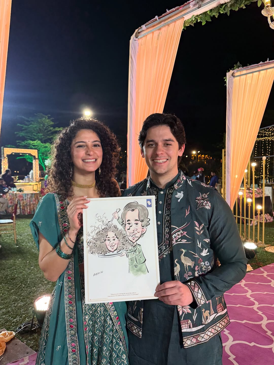 Night-time sangeet live caricature held by couple under outdoor wedding lights