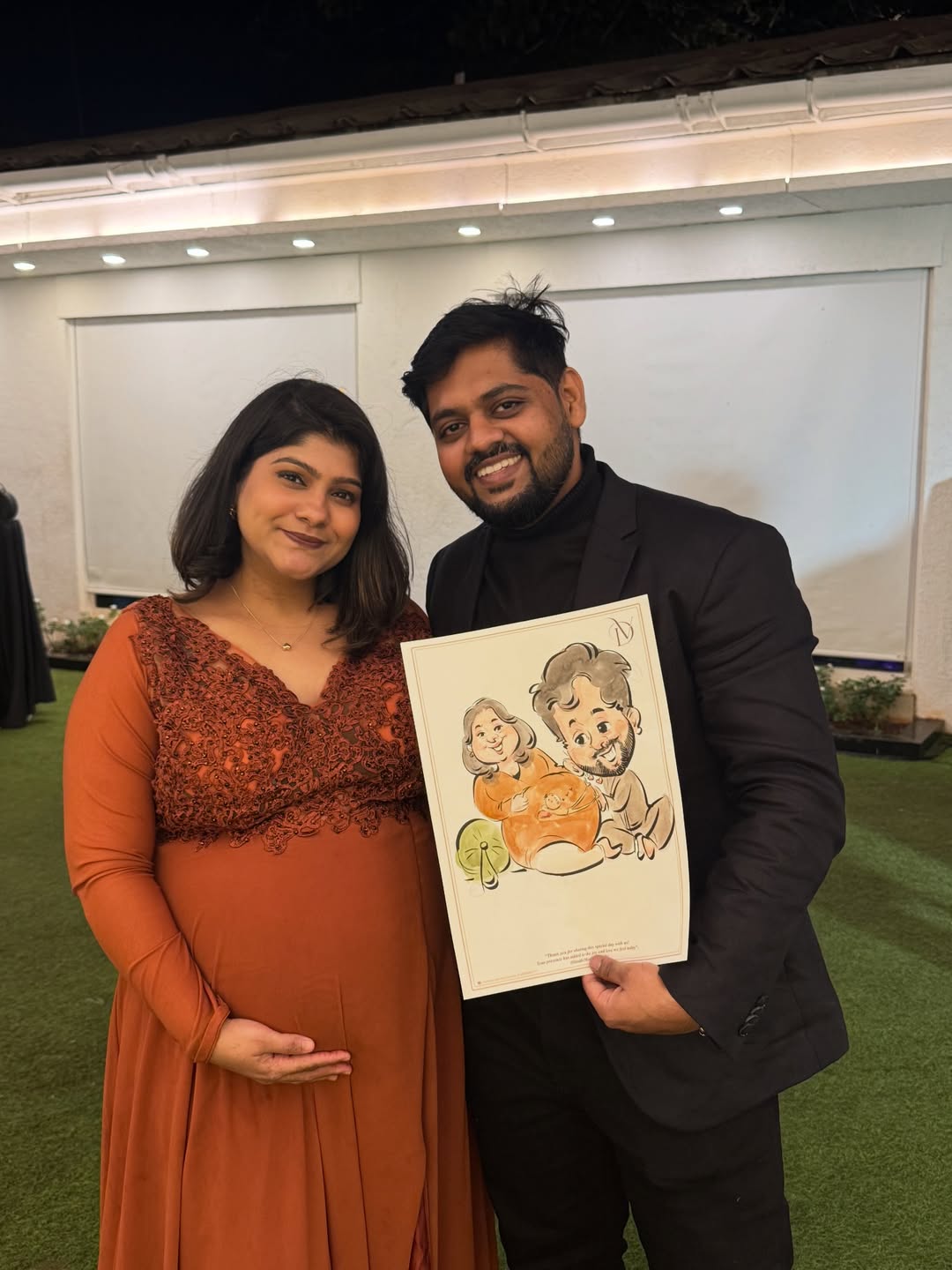 Expecting parents holding a live maternity caricature drawn at their baby shower
